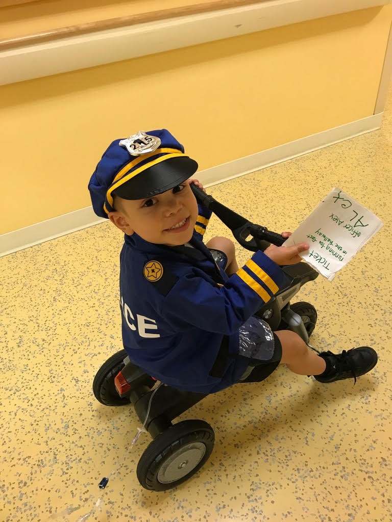 boy dressed up on a tri-cycle