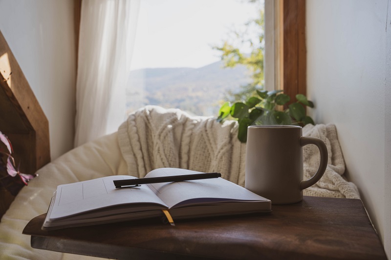 A cozy mental health break with an open journal, pen and cup of tea.
