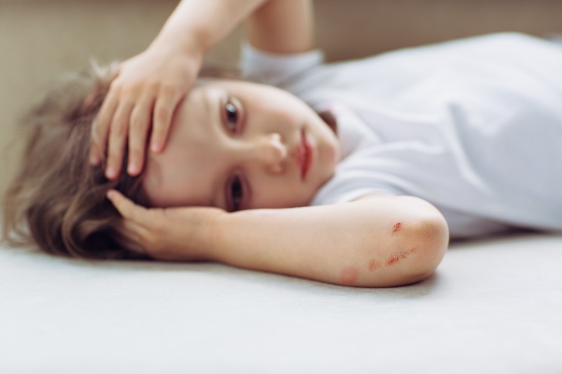 Child holding their head from injury, potentially a concussion