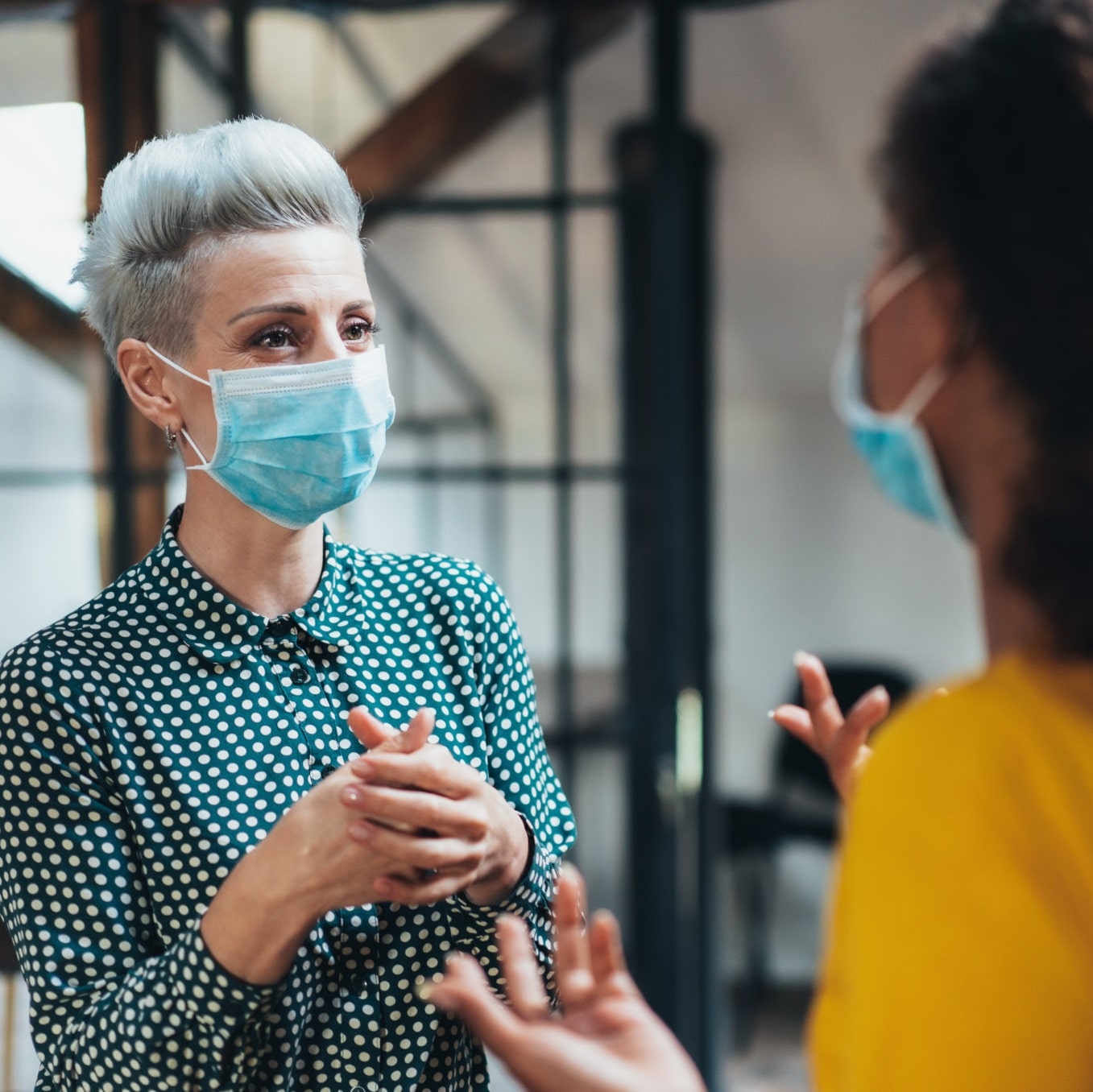 Two women talking with masks on
