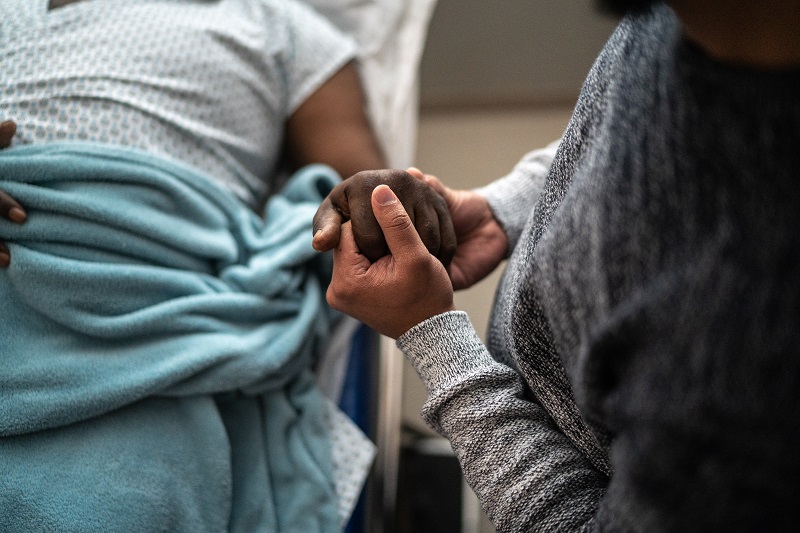 visitor holding patient's hand