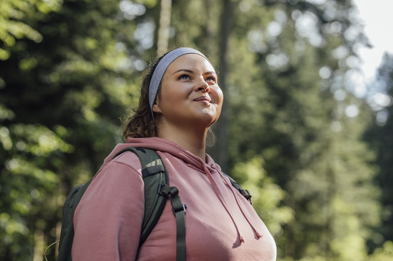 Happy woman with a backpack spending a day in nature.