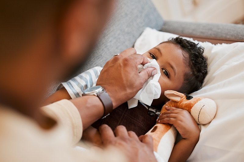 Parent taking care of sick child, blowing their nose. Cold remedies for children.