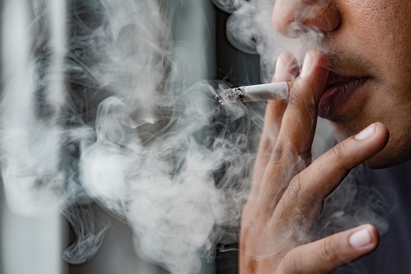 Close up of a woman's face smoking a cigarette and smoke coming out of her mouth
