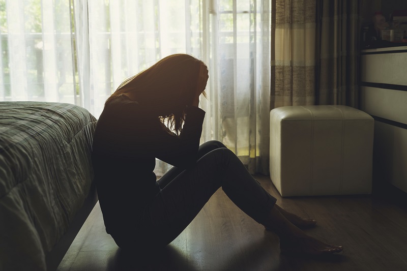 Woman sitting on the floor upset and emotional after a miscarriage