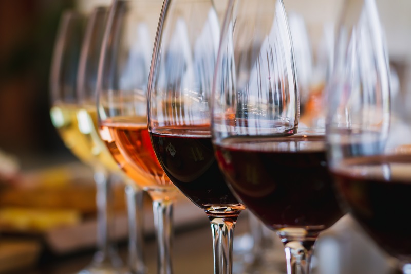 Close up view of wine glasses in a row, each having a different kind of wine it in.