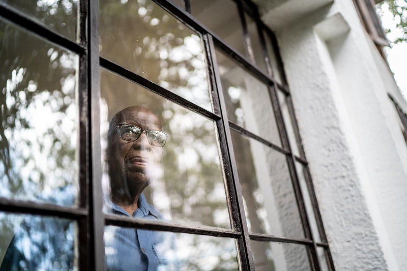 Senior man looking through the window at home