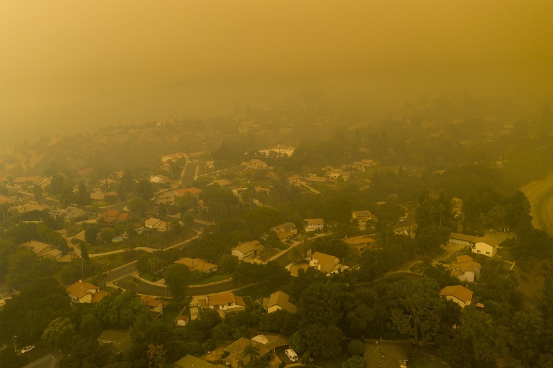 Aerial shot of a town and neighborhood covered in smoke from a fire, air pollution and hazardous air quality.