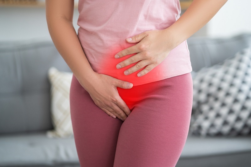 Woman with her hands on her lower stomach suffering from bladder issues.