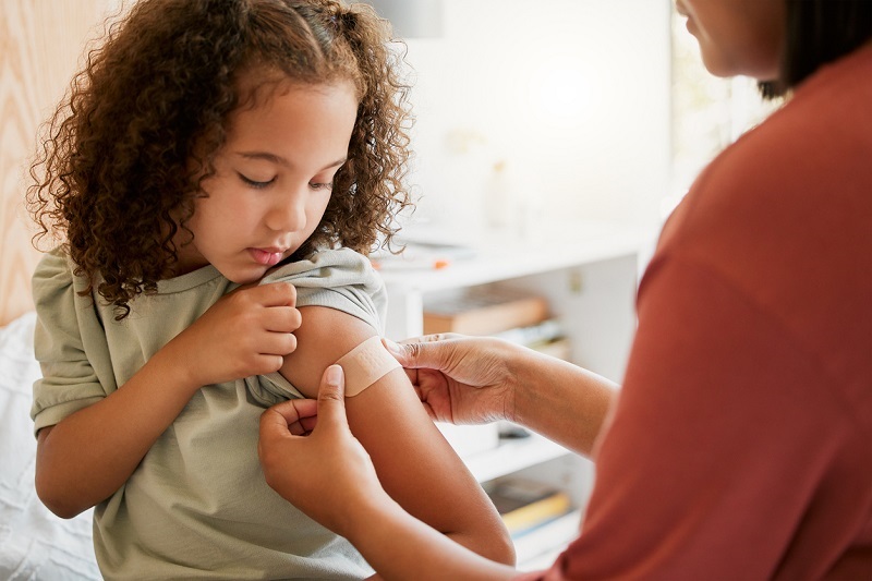 Young girl gets a bandaid placed on her arm after receiving the RSV antibody injection.