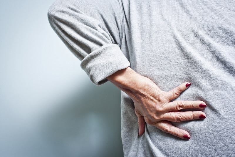 Elderly woman with a back ache from arthritis pain.