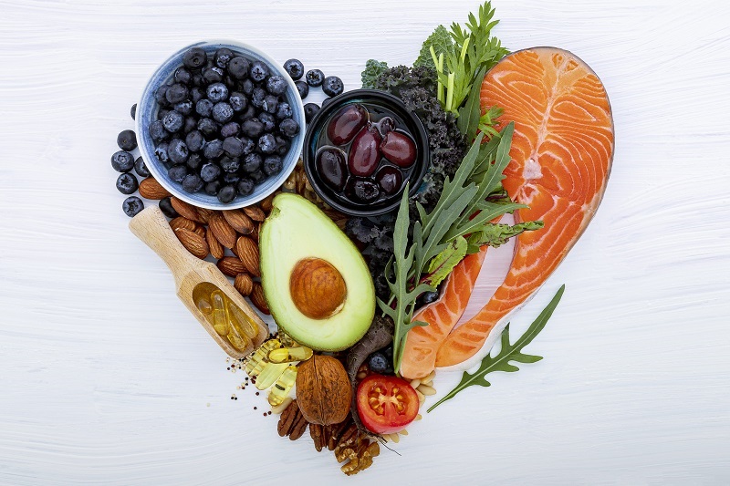 Heart shape of heart healthy foods. Ingredients for healthy foods selection on white wooden background.