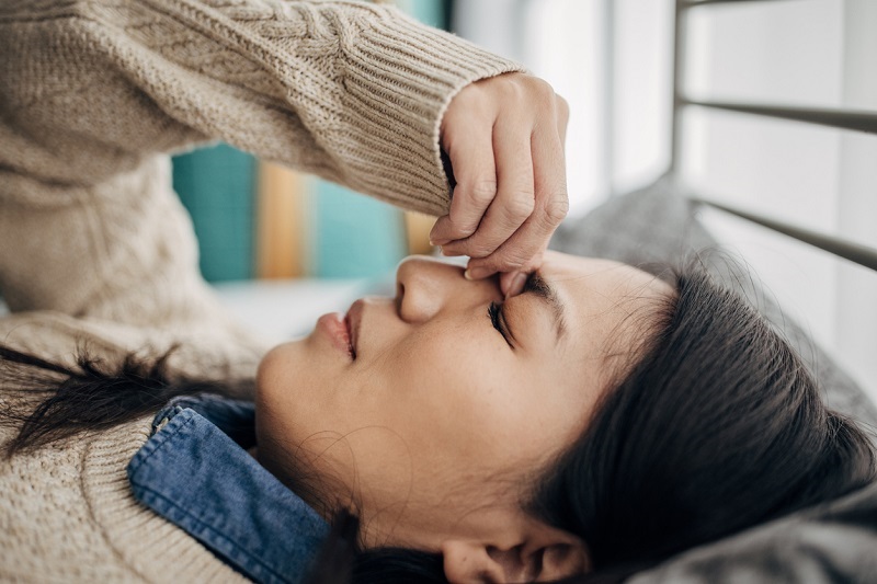 A woman lying with a severe headache.