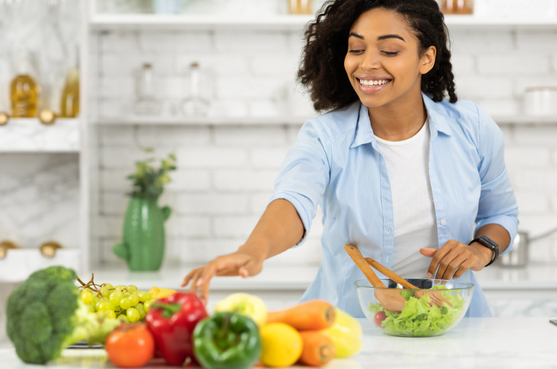 A Black woman prepares a healthy lunch for her family in a modern kitchen.