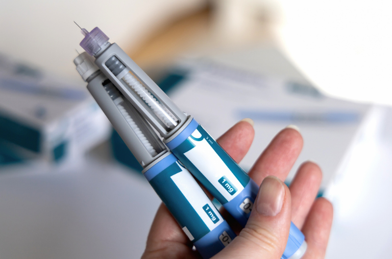 Hand holding two Ozempic injection pens for diabetics and weight loss.