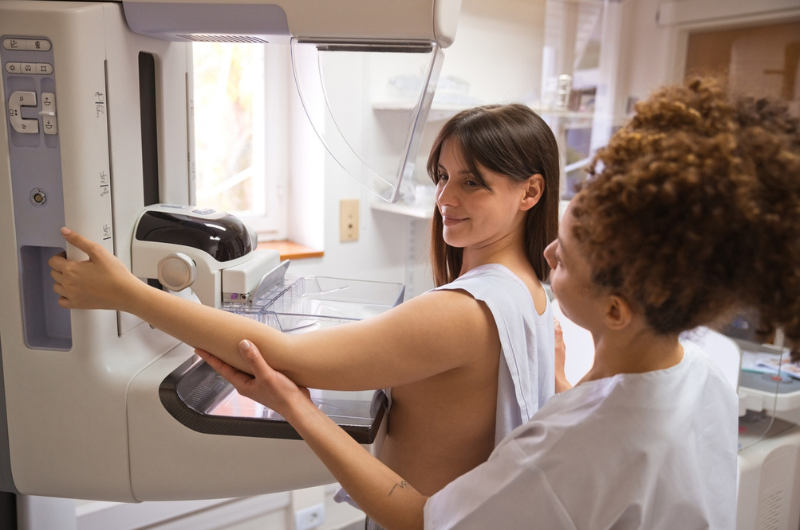 A health care professional prepares a female patient for a mammogram.