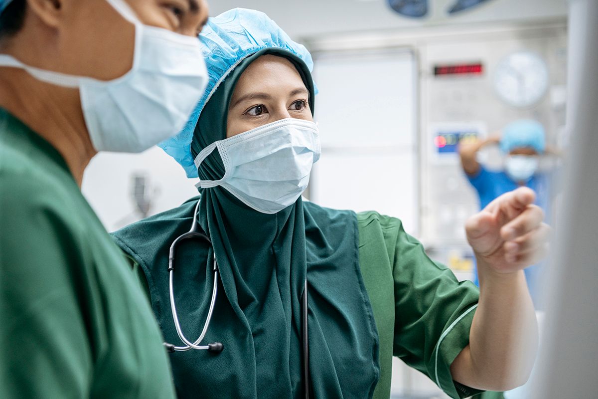 two physicians with masks on looking at a screen