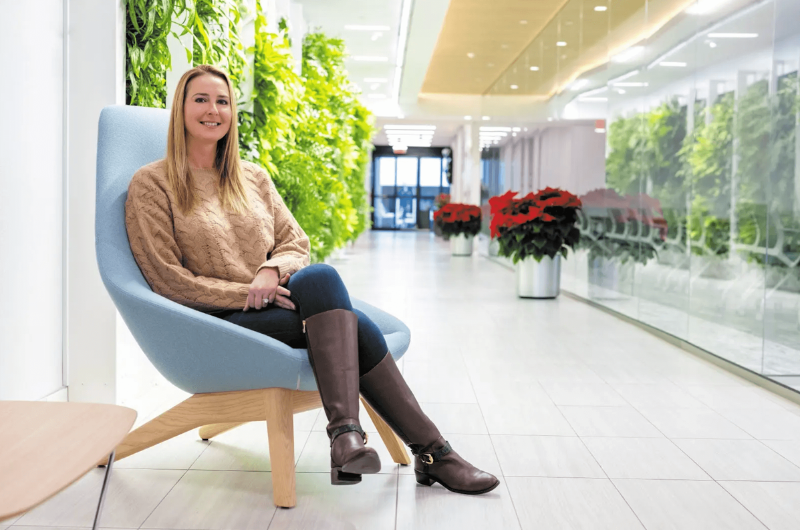 Nicole Mooney, a young mother of three, sits in a hospital lobby and smiles at the camera.