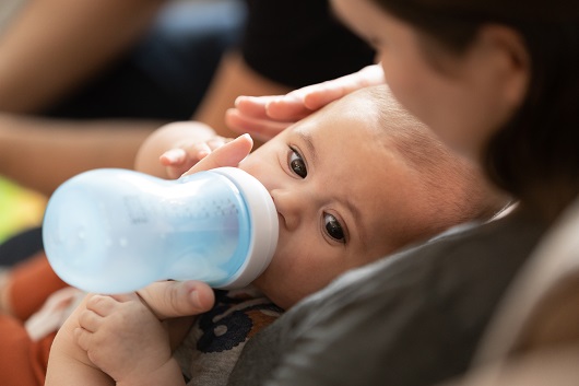 Baby Benny being held by his mother, drinking a bottle