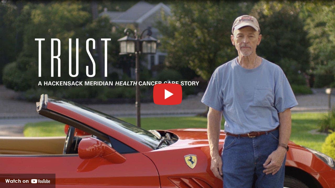 Cancer survivor standing beside red convertible