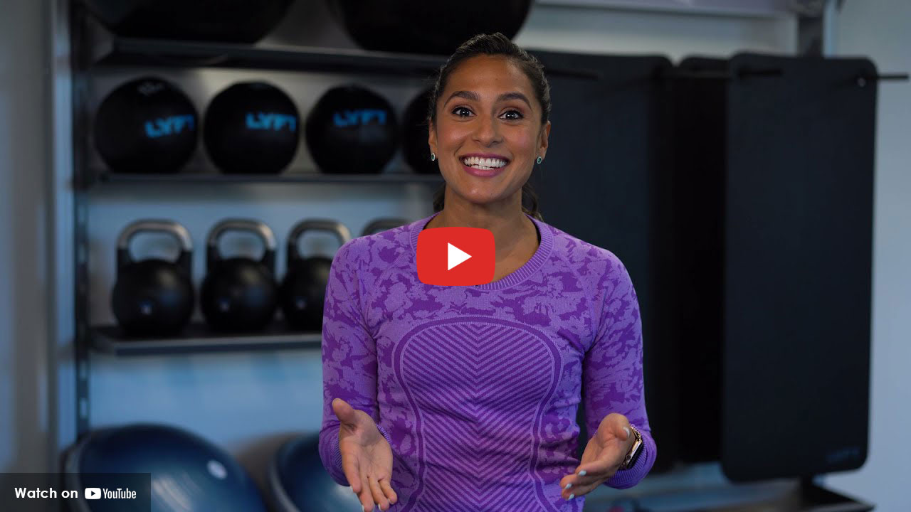 women  in purple shirt standing in front of exercise eqipment